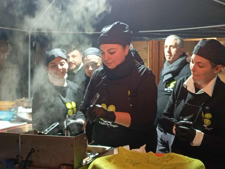 Le sorelle allo stand cucinano tra il fumo della piastra